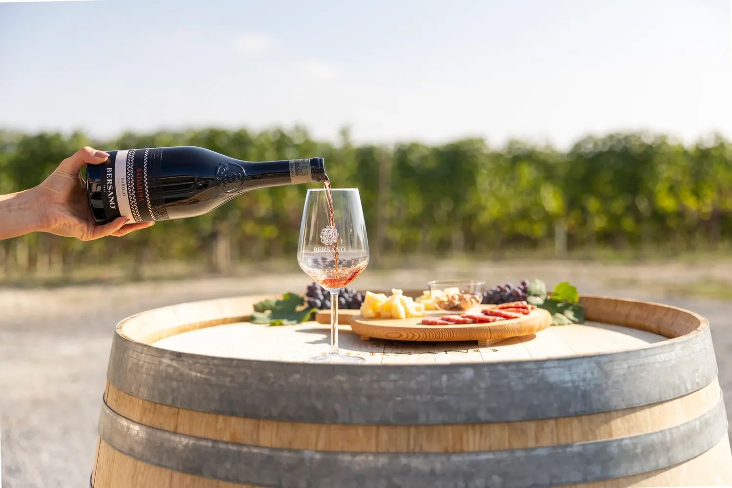 Barolo Bersano versato nel calice su una botte tra i vigneti